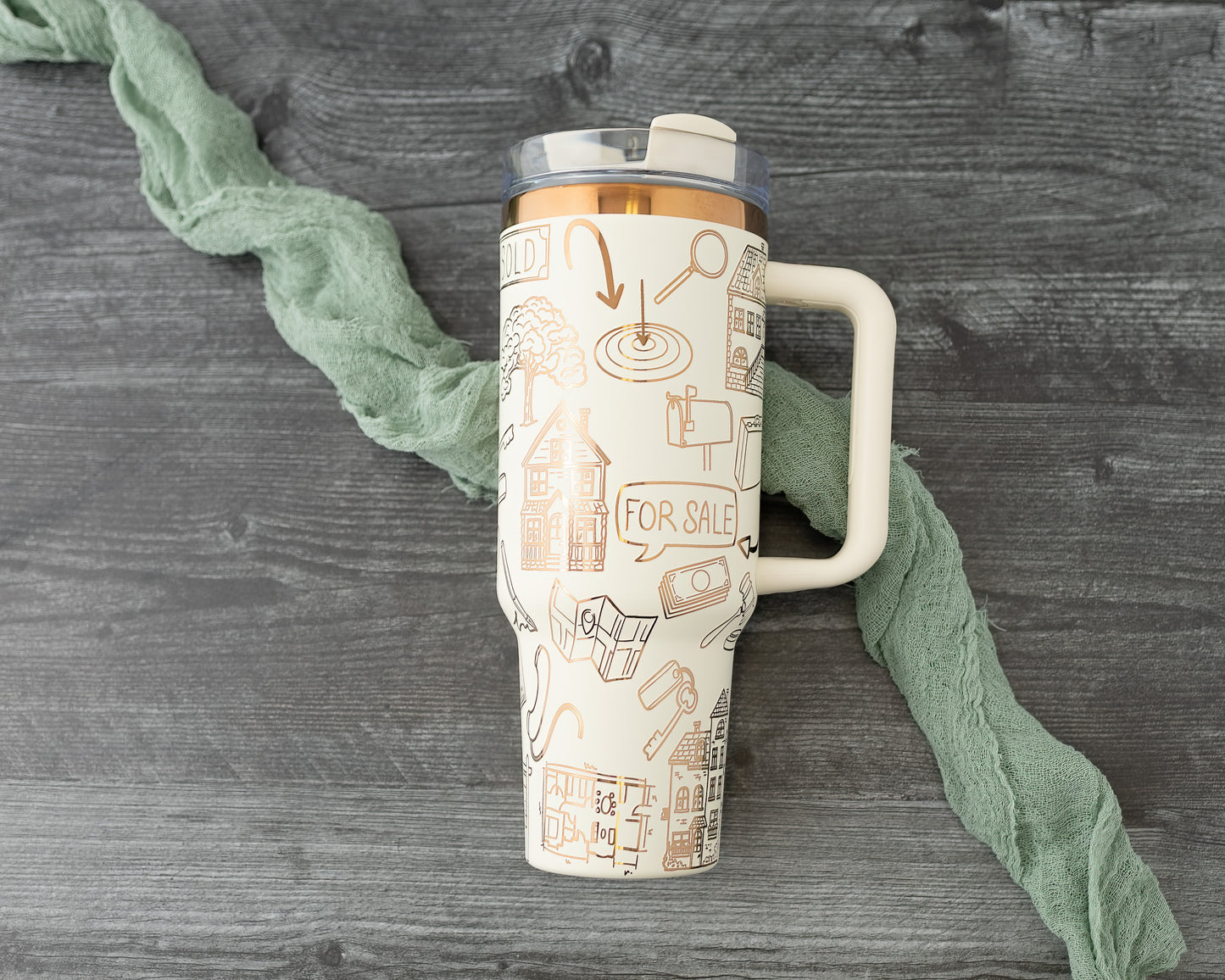 Tumbler with real estate-themed design on a wood background.
