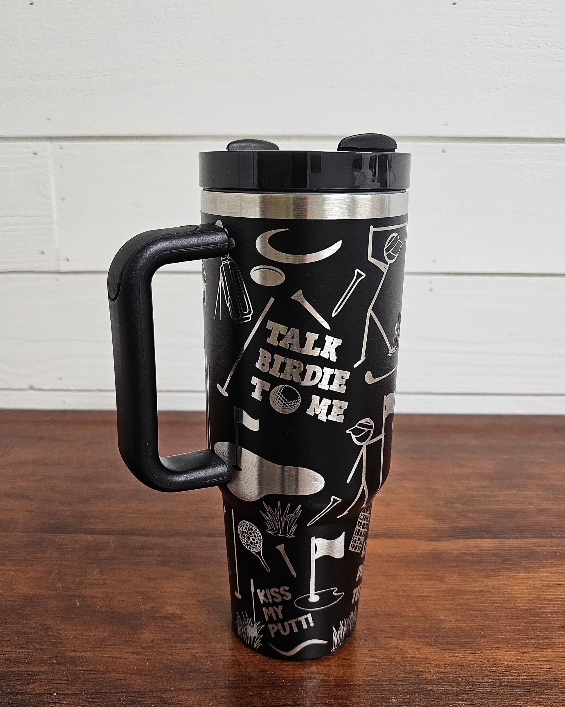 40oz tumbler in black with golf funny sarcastic sayings and cartoon doodles wrapped around the tumbler. Front view.