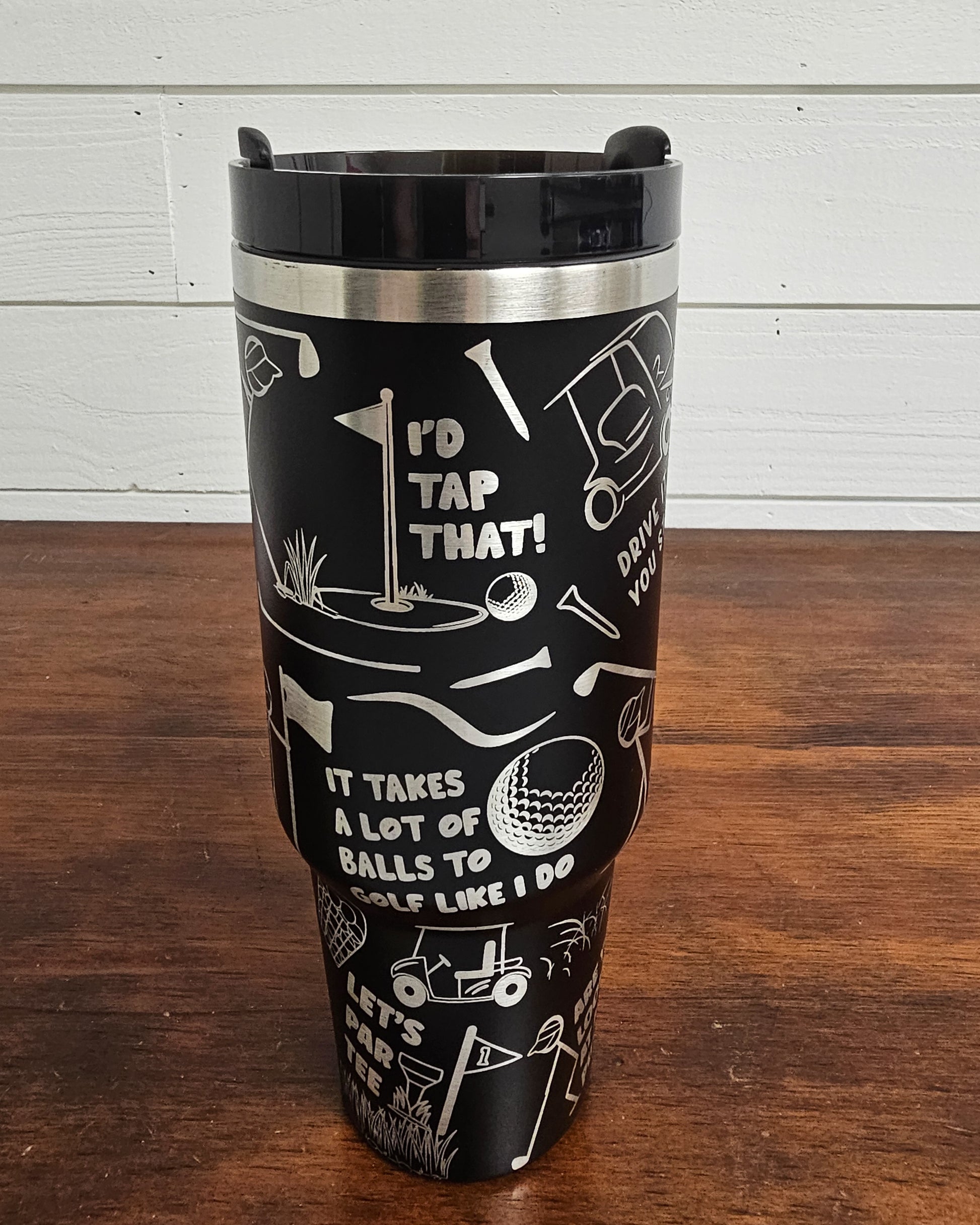 40 oz tumbler in black with golf funny sarcastic sayings and cartoon doodles wrapped around the tumbler. Side view.