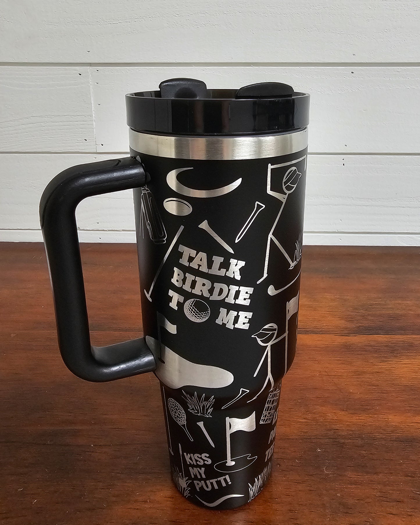 40 oz tumbler in black with golf funny sarcastic sayings and cartoon doodles wrapped around the tumbler. Front view.