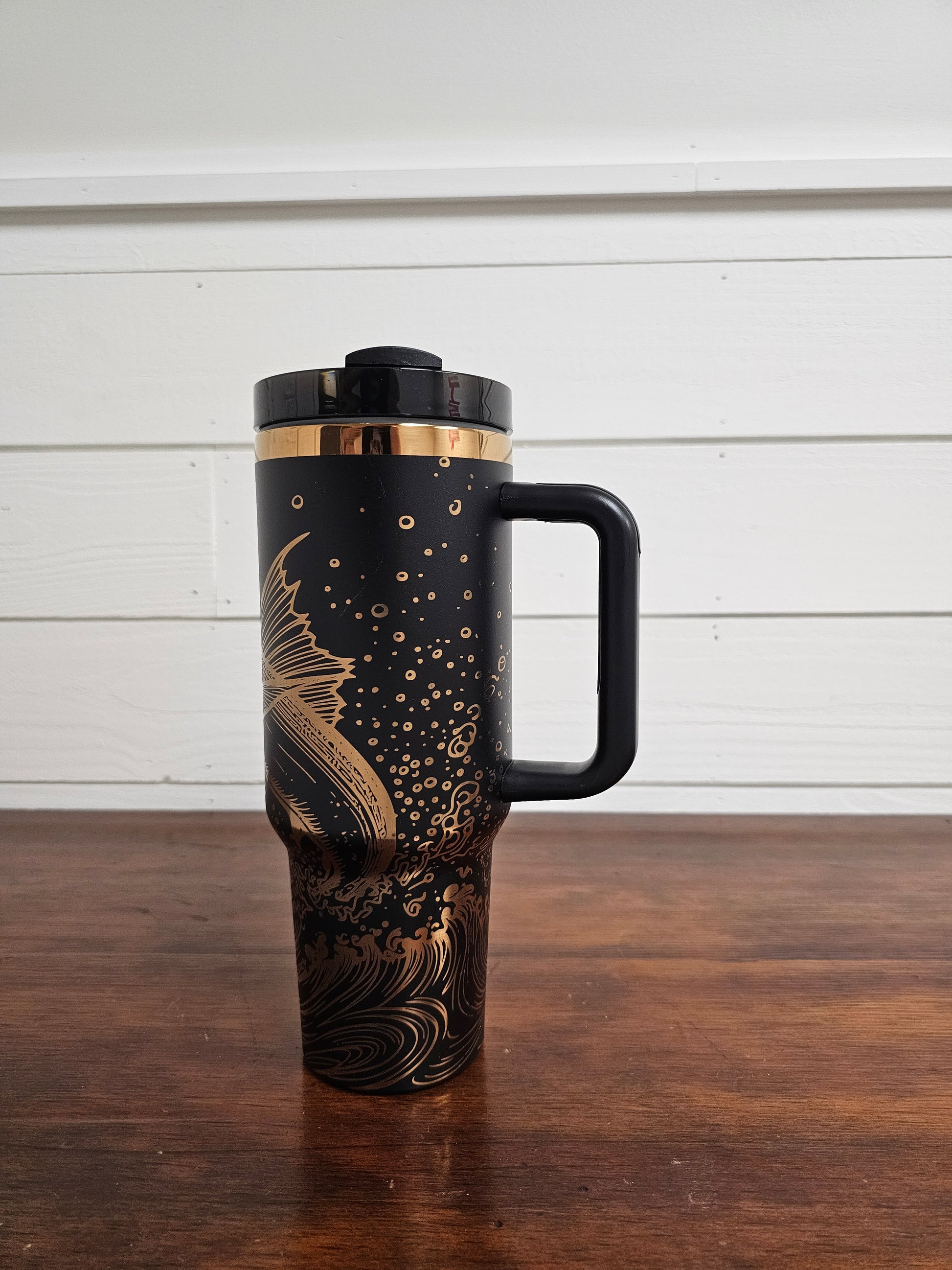 Laser engraved black and copper 40oz stainless steel tumbler with white marlin leaping out of the ocean.