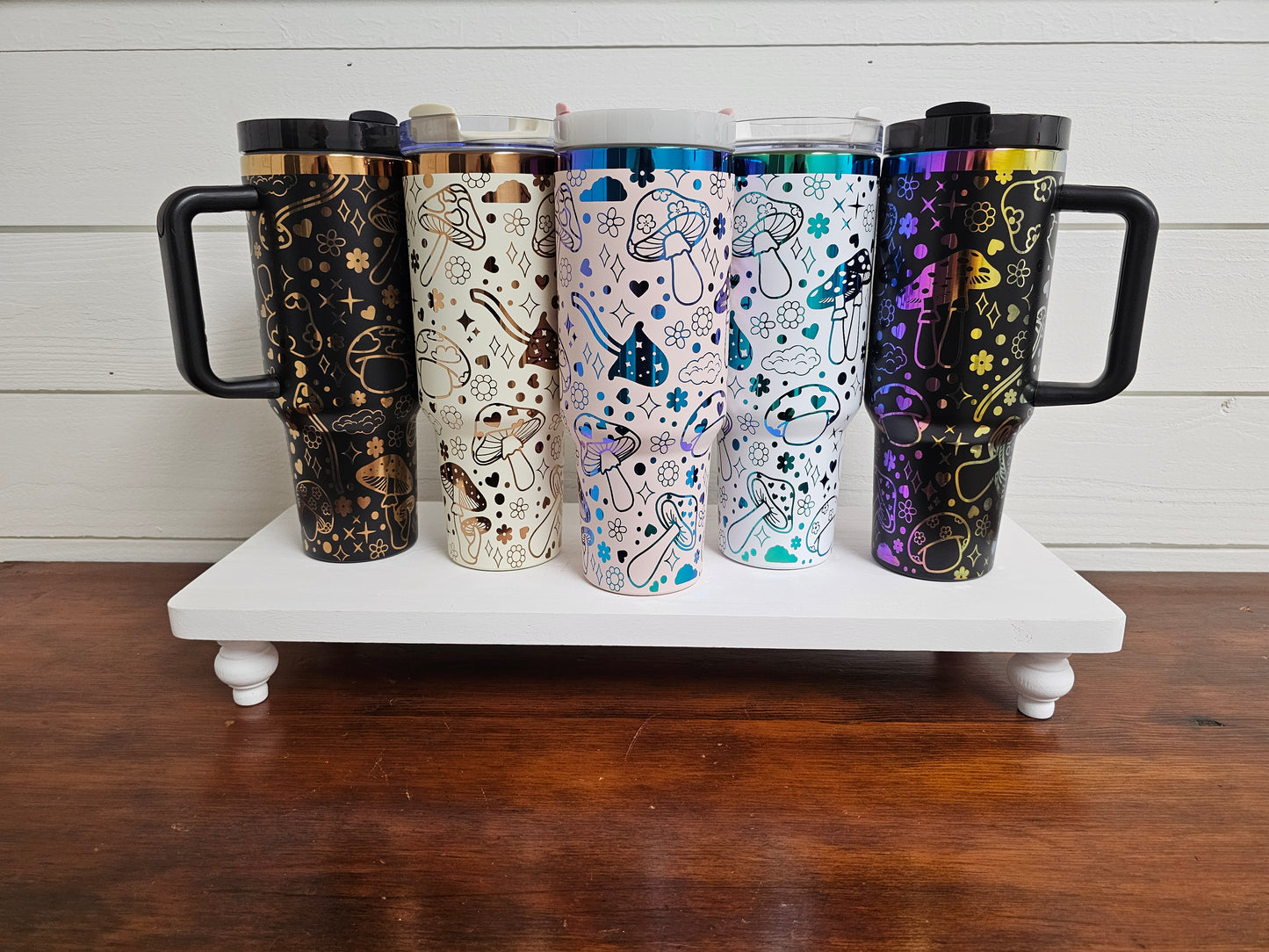 40oz tumblers in pink, black, white and rainbow and black and cream with copper with magic mushroom wrap design. 
