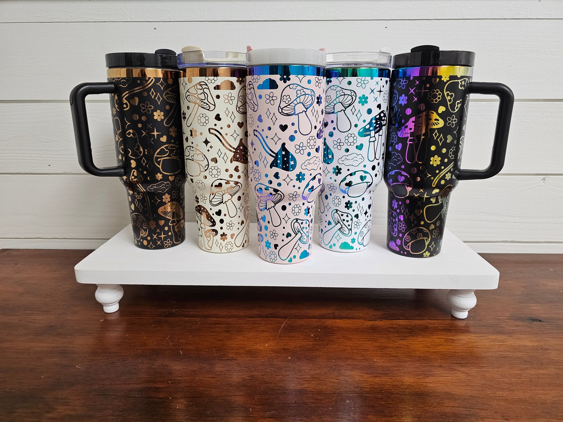 40oz tumblers in pink, black, white and rainbow and black and cream with copper with magic mushroom wrap design. 