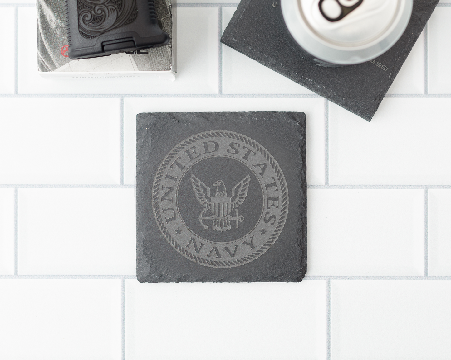 Slate coaster with United States Navy emblem on a white tiled surface