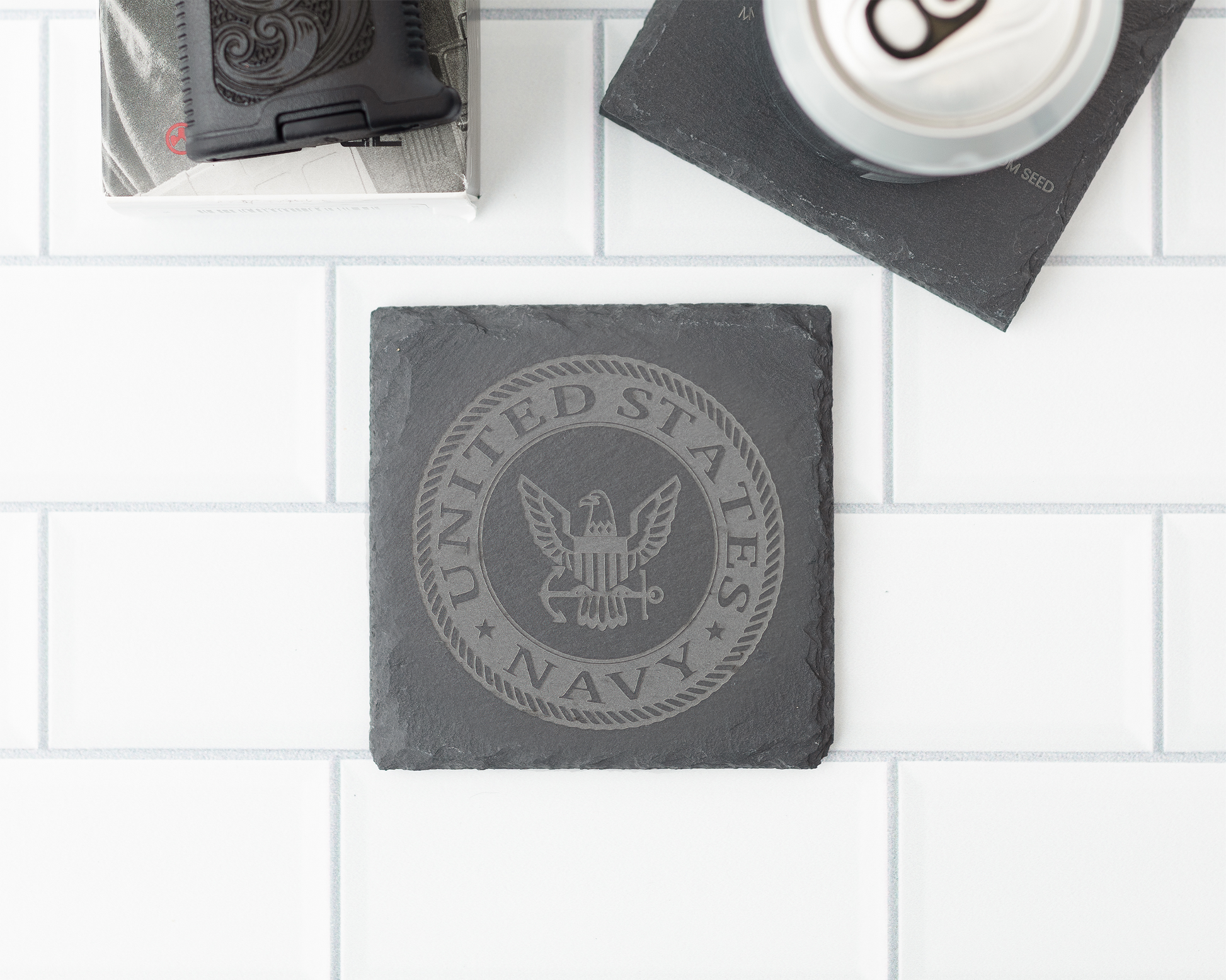 Slate coaster with United States Navy emblem on a white tiled surface
