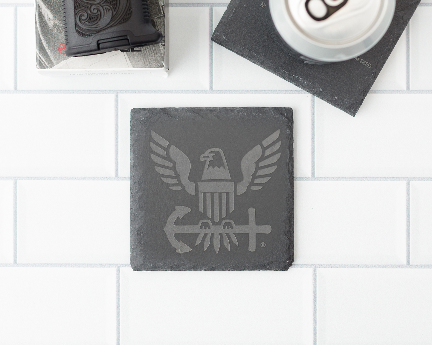Slate coaster with engraved design on a white tiled surface