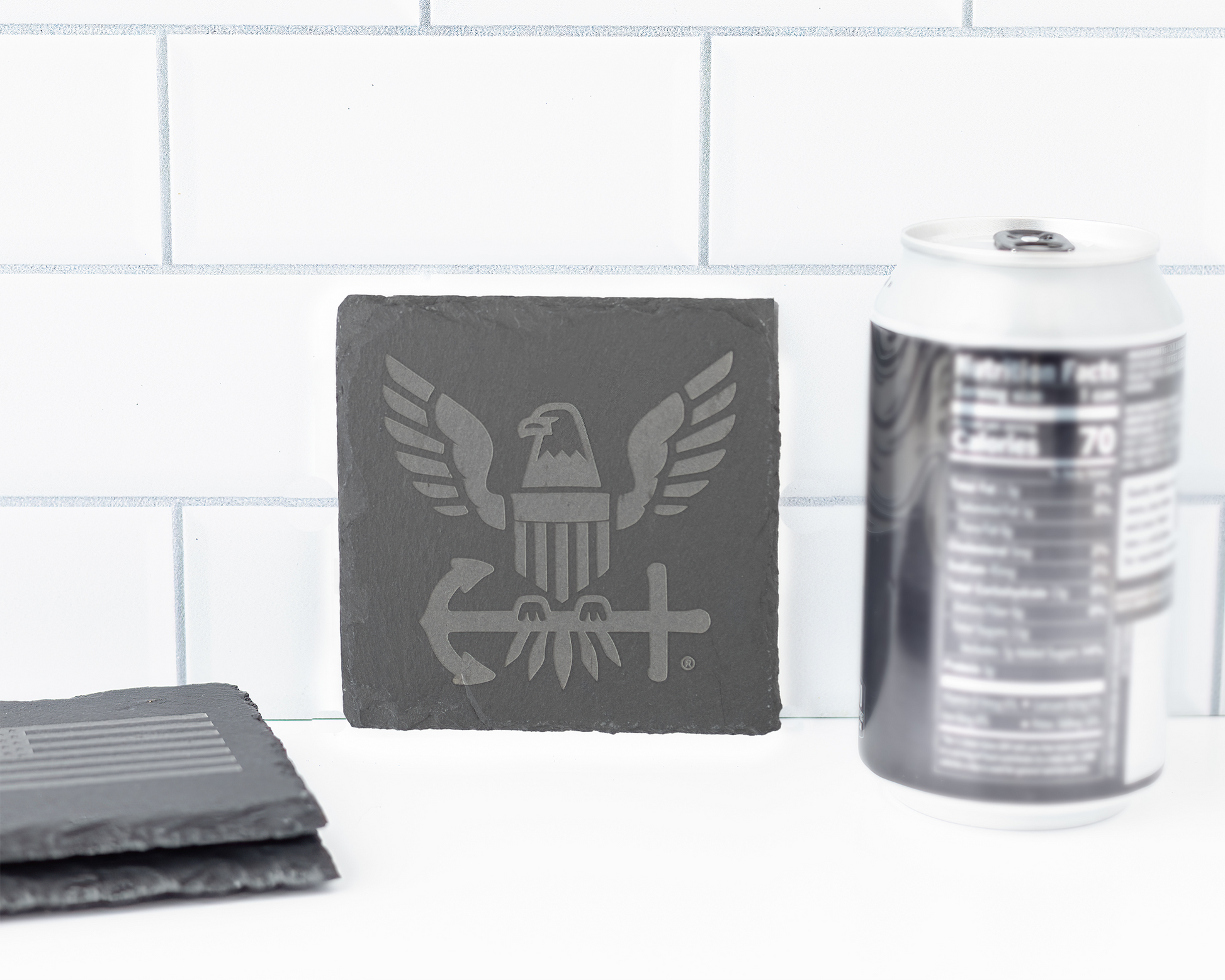 Set of gray coasters with a logo on a white surface with a tiled wall background