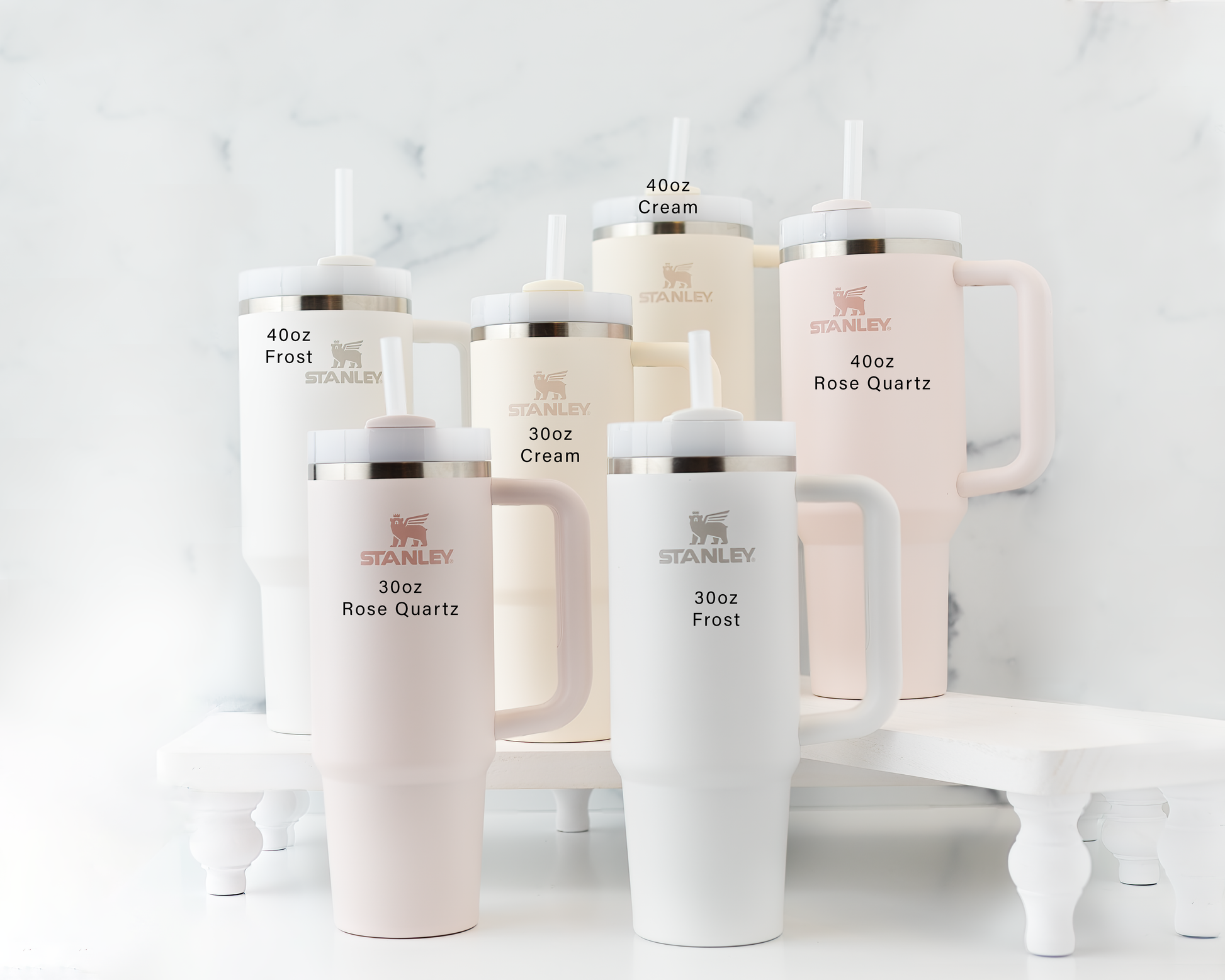 Laser engraved Stanley tumblers in frost, rose quartz, and cream colors in 30oz and 40oz sizes displayed together on a marbled background