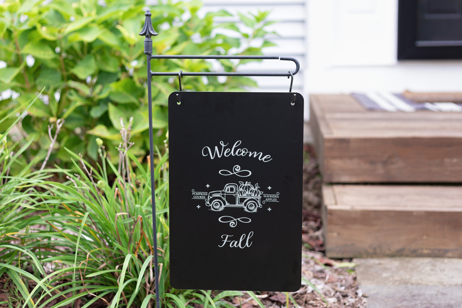Decorative garden sign with 'Welcome Fall' text on a stand outdoors.