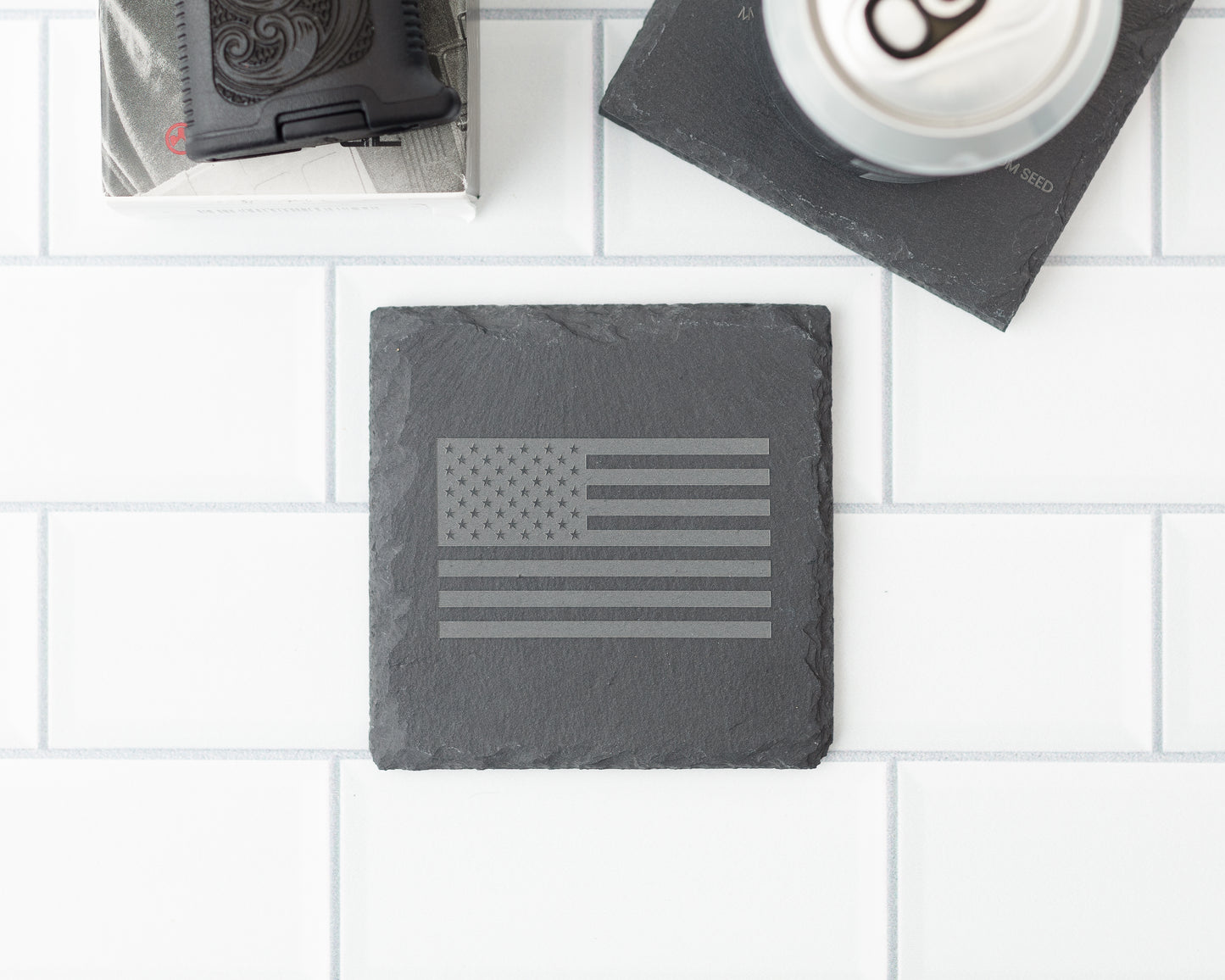 Slate coaster with American flag design on a white tiled surface