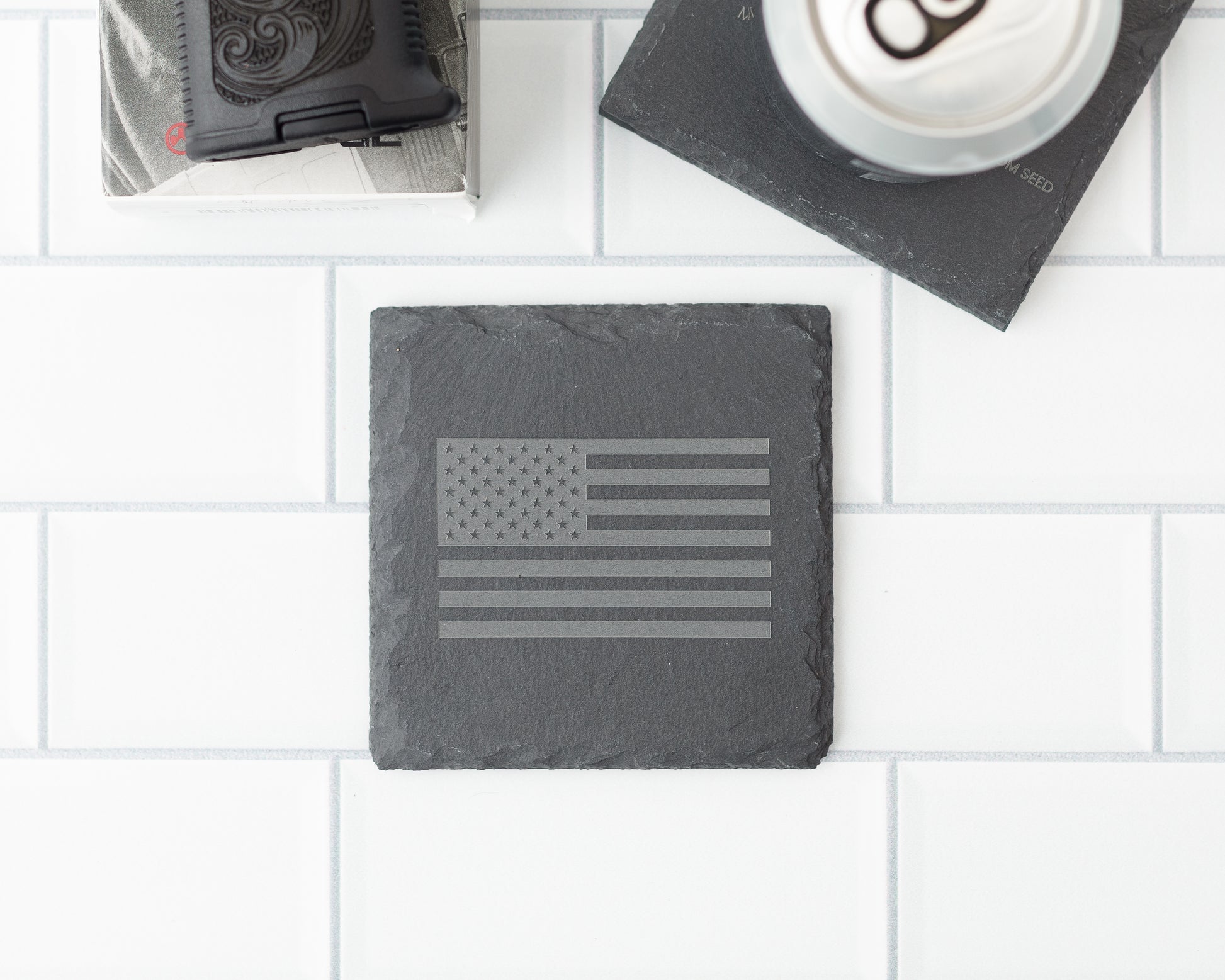 Slate coaster with American flag design on a white tiled surface