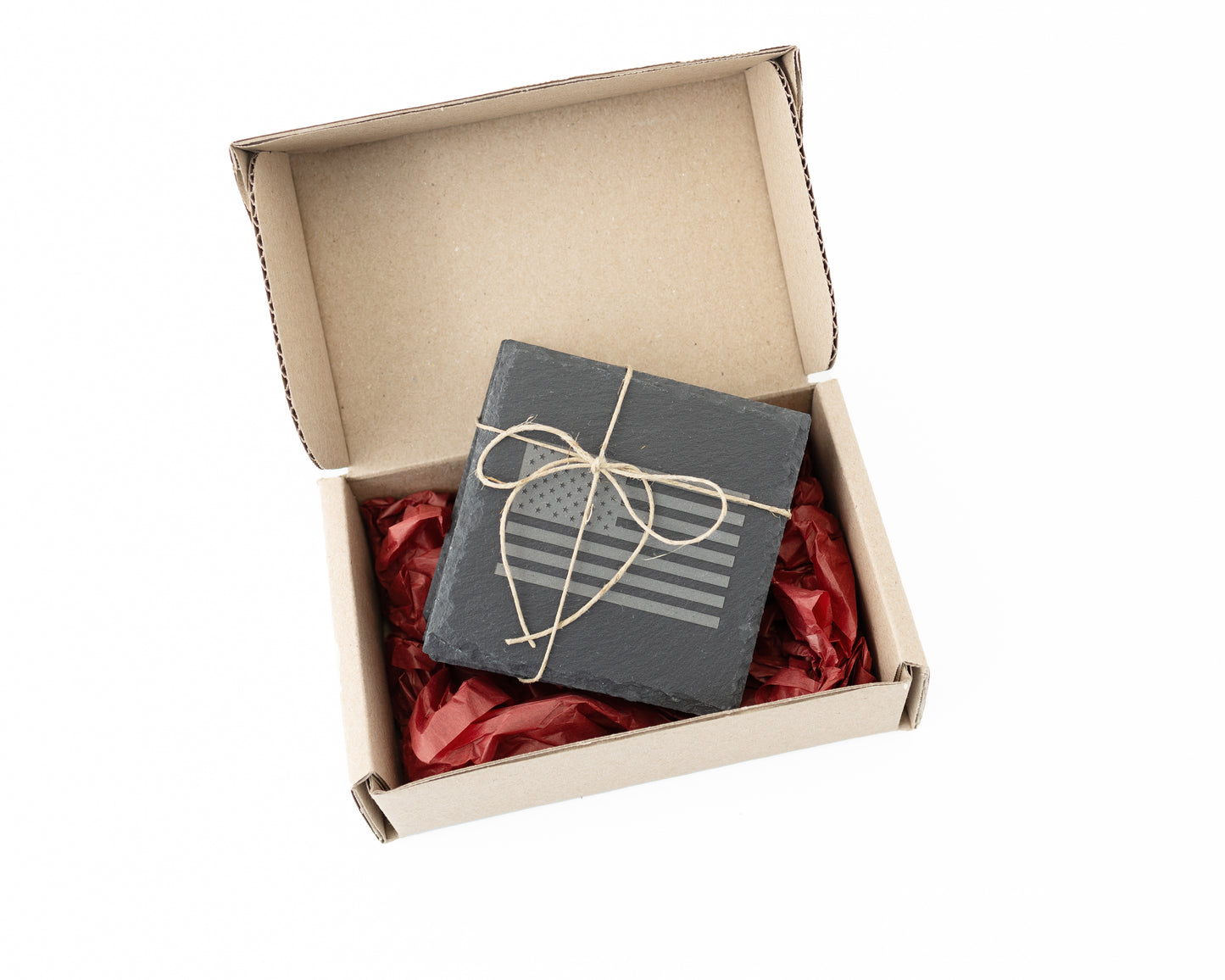 Gift box with red tissue and slate coasters inside on a white background