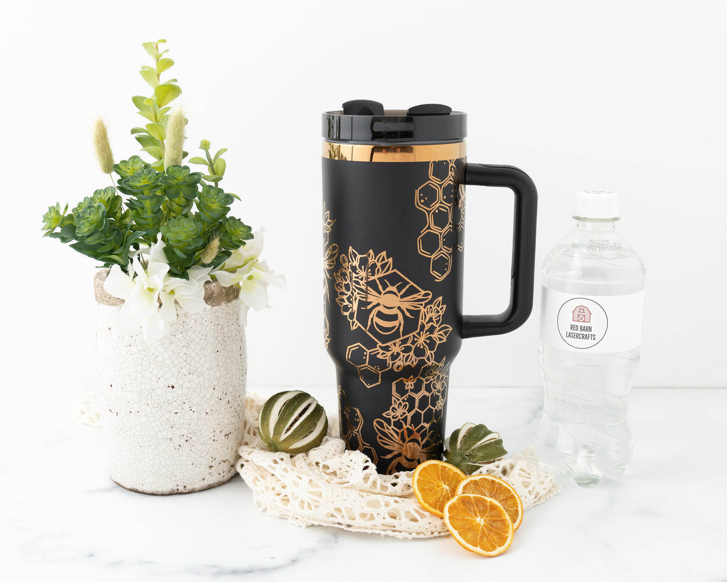 Laser engraved black and copper 40oz stainless steel tumbler with bumble bee and honeycomb design. Shown with a water bottle for size comparison.