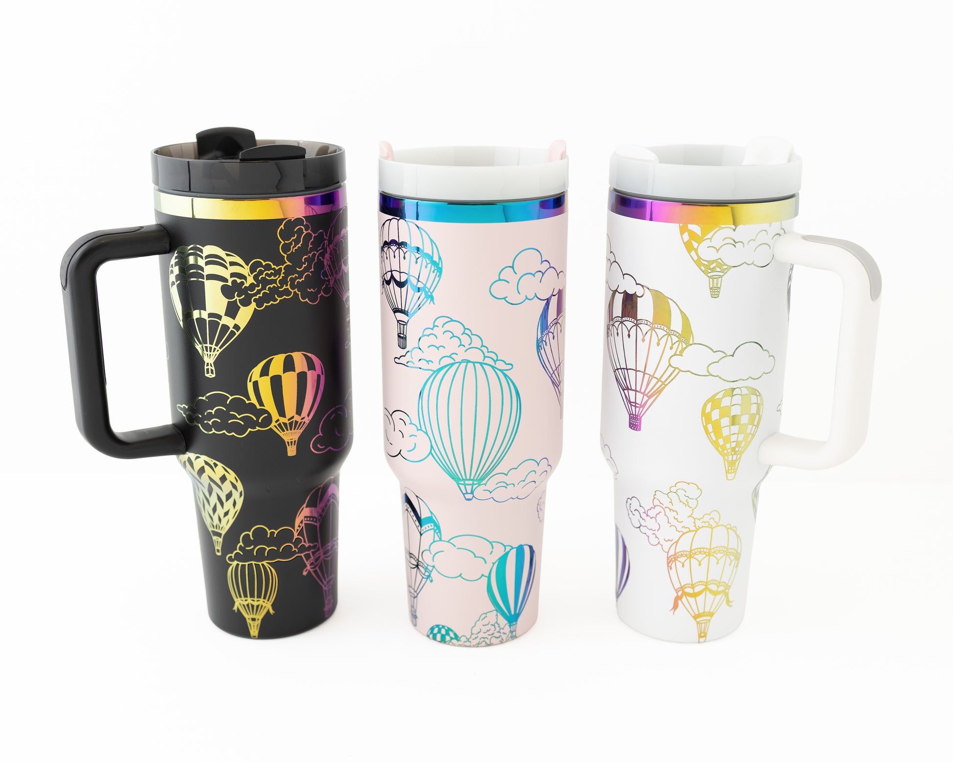 Black, pink, white and rainbow 40oz tumblers with hot air balloon design shown together on a white background.