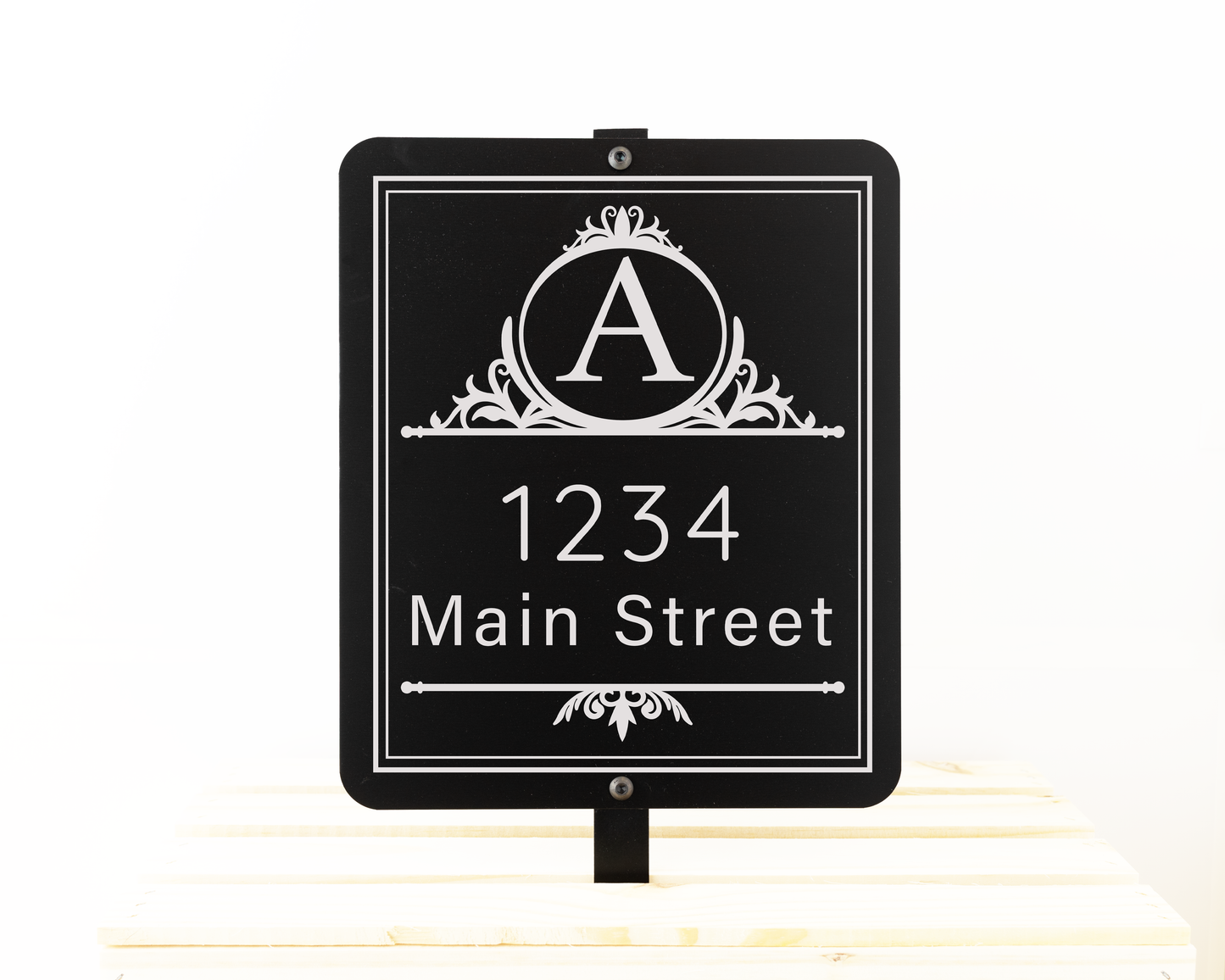 Black garden sign engraved with a decorative monogram and an address. Shown on a white background.
