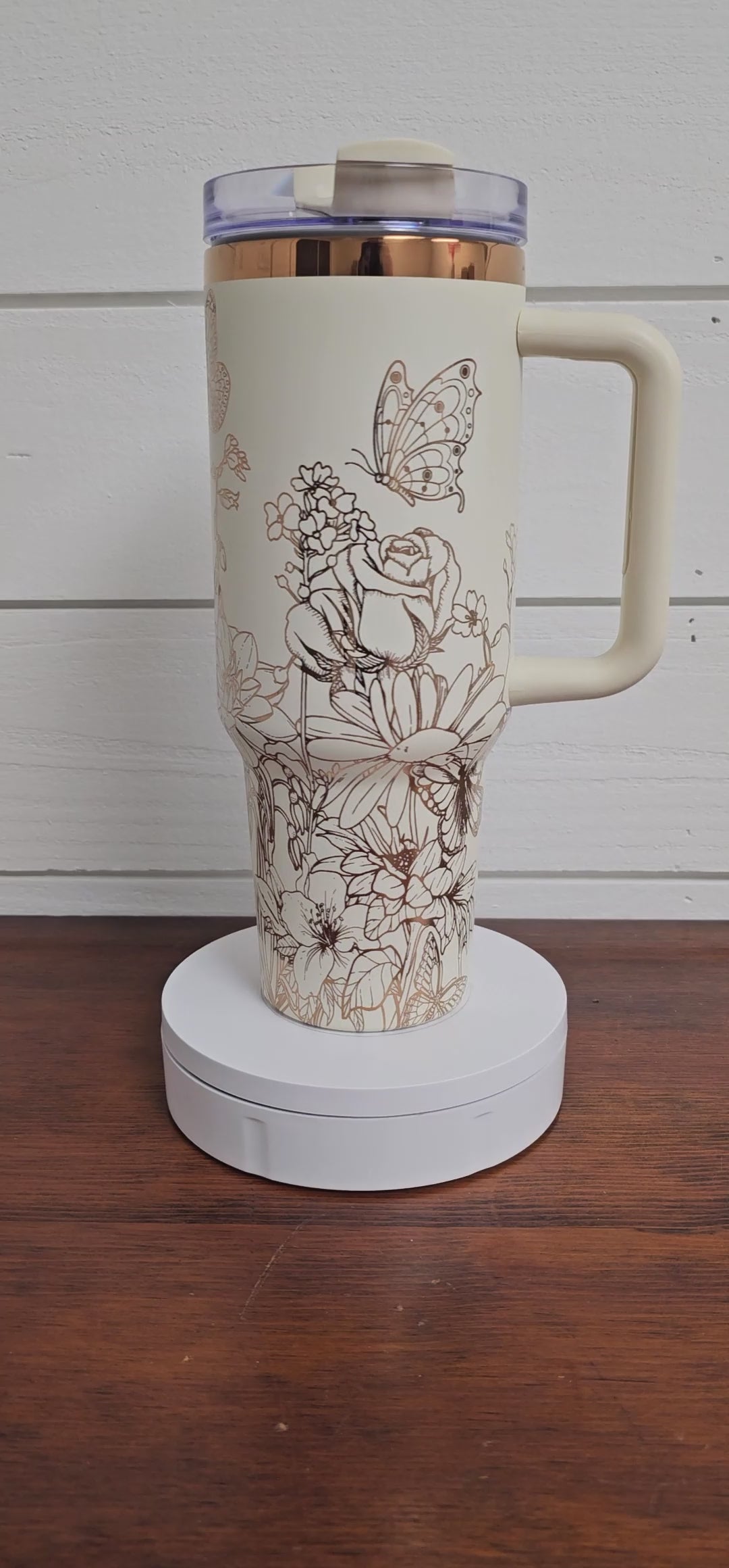 Cream and copper tumbler with floral and butterfly design on a white shiplap background